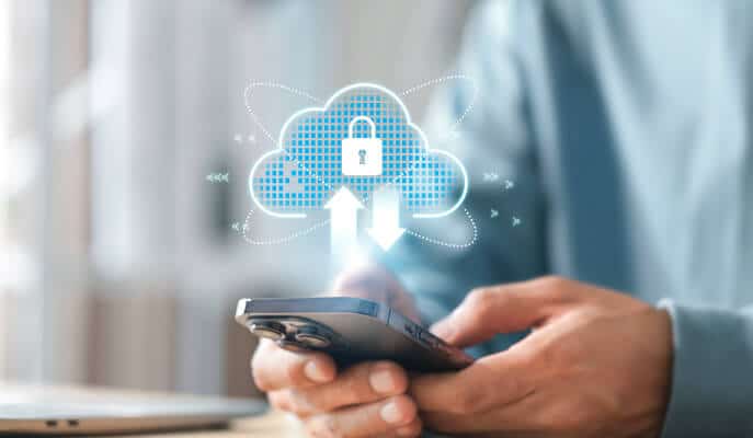 A person holds a smartphone with a digital cloud icon above, featuring a lock and arrows. This symbolizes secure cloud data transfer and encryption.