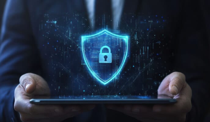 A person holds a tablet displaying a glowing digital shield and lock icon, symbolizing cybersecurity.