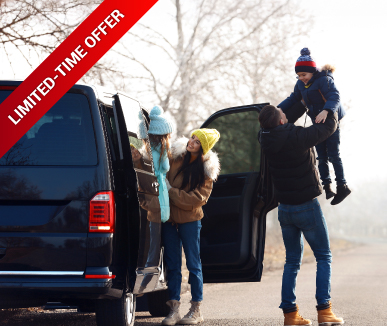 A family by a black van on a sunny winter day. A man lifts a child in winter clothing, while a woman and a girl in colorful hats stand nearby. "Limited-Time Offer" text appears on a red banner.