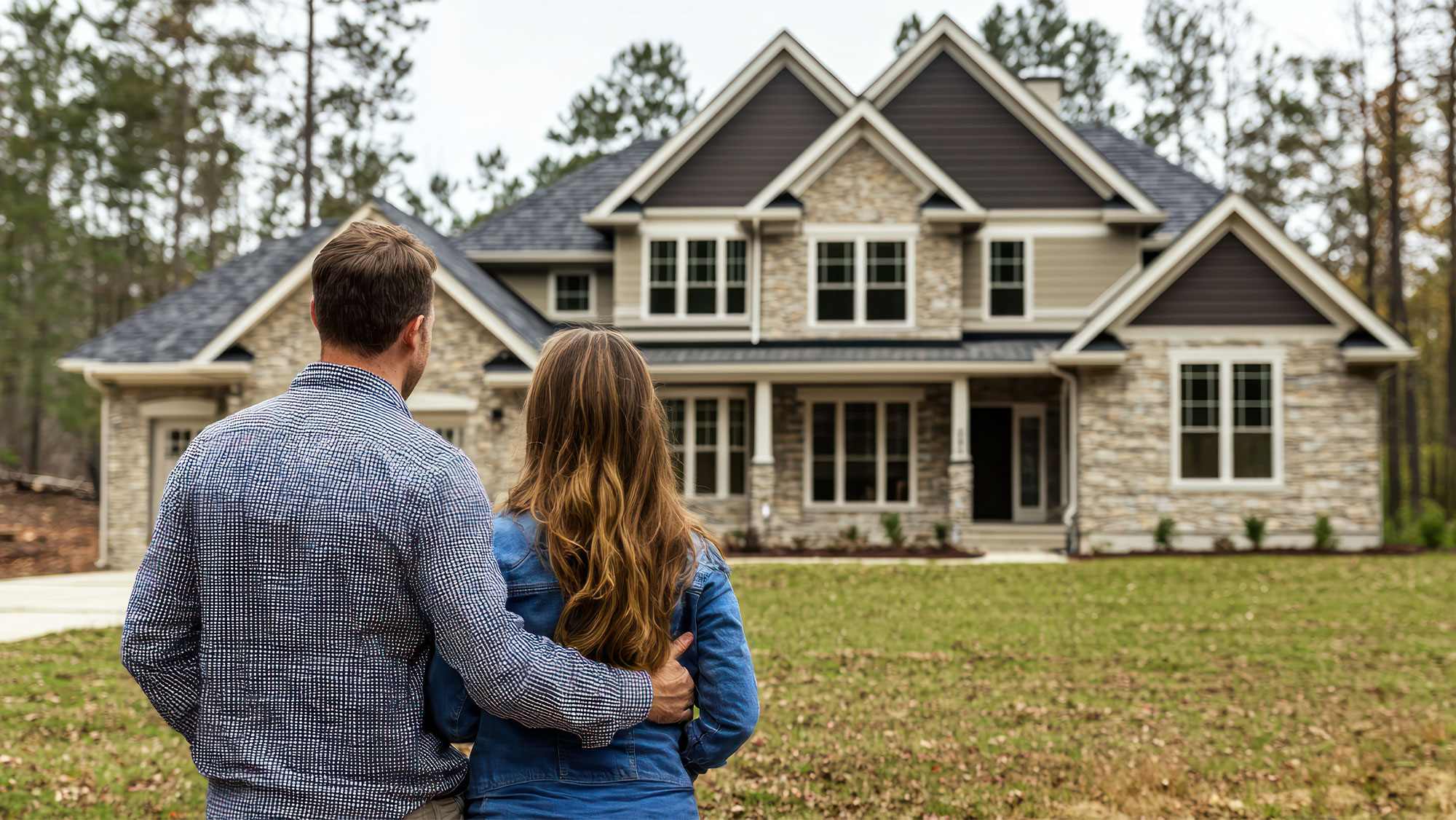 Young couple with back's turned to camera staring at large house in the distance.