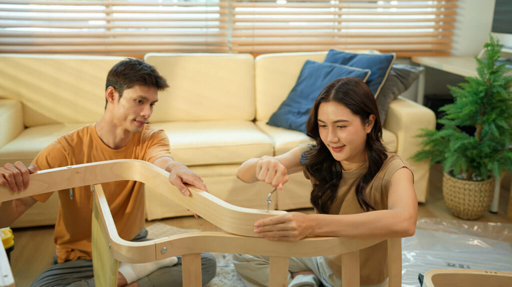 Couple putting chair together sitting on floor of living room.